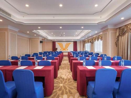 une salle de conférence avec des tables rouges et des chaises bleues dans l'établissement Vienna Hotel Jiangsu Changzhou Zouqu Lamp Market, à Beigang