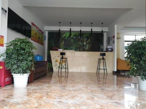 ニンティ市にあるShell Linzhi Bayi Area G318 Shuangyong Road Hotelの植物の備わる椅子2脚とカウンター付きの部屋