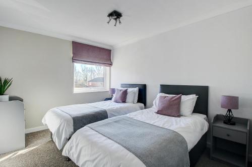 a bedroom with two beds and a window at Milton Keynes - Neath Hill in Milton Keynes