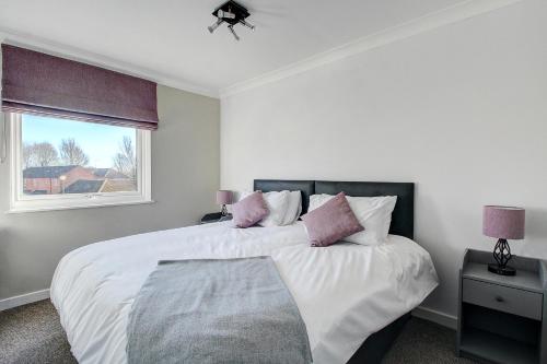 a white bedroom with a large bed with pink pillows at Milton Keynes - Neath Hill in Milton Keynes