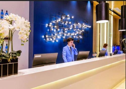 a man standing in front of a reception desk at Echarm Hotel Guiyang Longdongbao International Airport Outlets in Guiyang