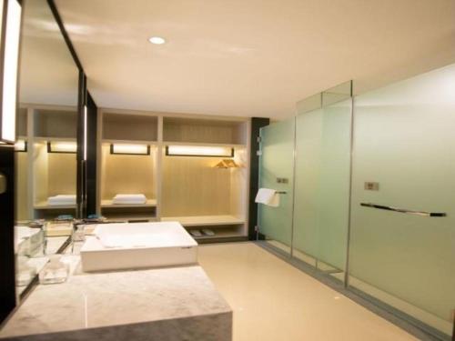 長春的住宿－Echarm Hotel Changchun Yiqi Automotive Trade City Wanda，一间带水槽和玻璃淋浴的浴室