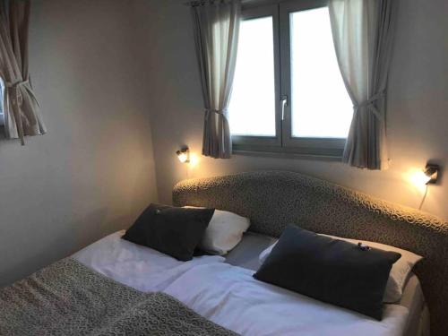 ein Schlafzimmer mit einem Bett mit zwei Kissen und einem Fenster in der Unterkunft mini Haus mit Pergola -NL-00000196 in Tenero