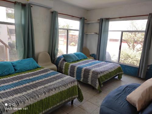 two beds in a room with windows at Luz del Mar Paredón in Sipacate