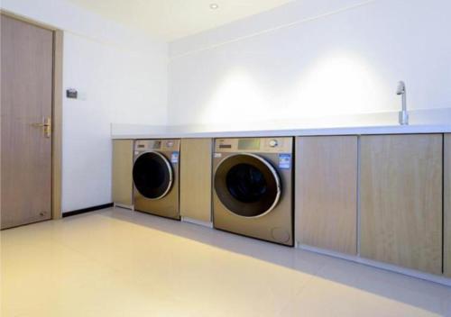 a laundry room with two washing machines in it at Echarm Hotel Wuhan Huangpu Erqi Xiaolu Metro Station in Jiang'an
