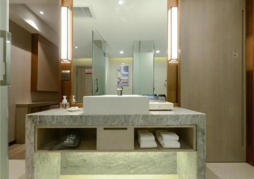 a bathroom with a sink and a mirror at Echarm Hotel Wuhan Huangpu Erqi Xiaolu Metro Station in Jiang'an
