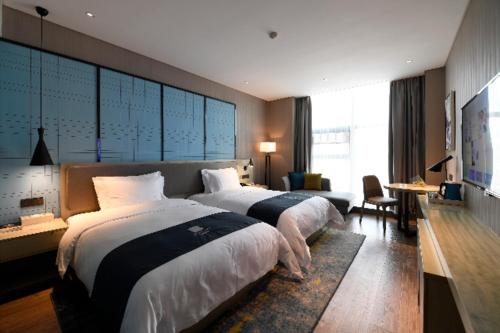 um quarto de hotel com duas camas e uma televisão em Echarm Hotel Huaihua Vocational College em Huaihua