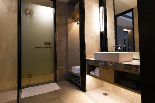 uma casa de banho com um lavatório e um chuveiro com um espelho. em Echarm Hotel Huaihua Vocational College em Huaihua
