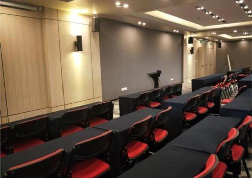 a lecture hall with black tables and red chairs at Echarm Hotel Changchun Guanggu Street in Changchun