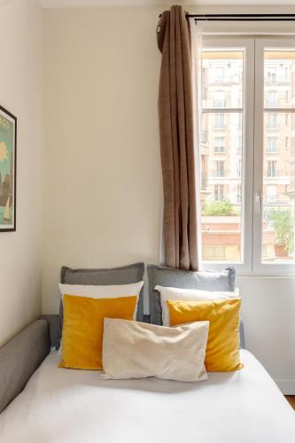 une chambre avec un lit avec des oreillers jaunes et une fenêtre dans l'établissement Paris 15 Cocoon, à Paris