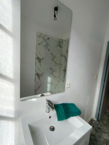 a white bathroom with a mirror and a sink at L'escale de Compostelle, centre ville à 5 minutes du Canal in Moissac