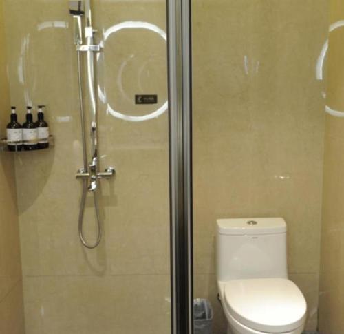 a bathroom with a shower with a toilet and a glass shower door at Echeng Hotel Beihai Hunan Road Old Street in Gaode