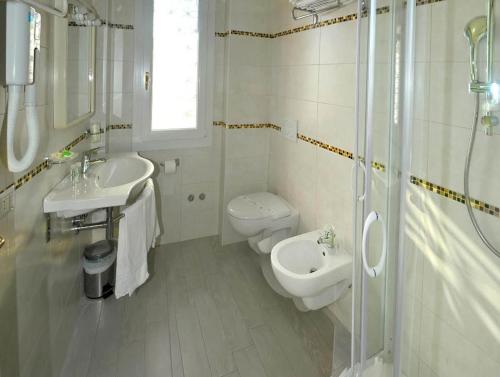 a bathroom with a toilet and a sink and a shower at Hotel Zenith in Cervia