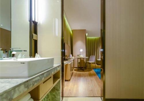 a bathroom with a white sink and a desk at Echarm Hotel Zunyi Conference Site Gang'ao Branch in Zunyi