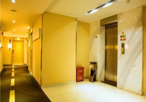 a hallway of an office with yellow walls and a elevator at JTOUR Inn Wuzhou Arcade City Sanzongfu in Wuzhou