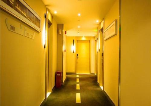 a corridor of a hallway with yellow walls and a yellow door at JTOUR Inn Wuzhou Arcade City Sanzongfu in Wuzhou