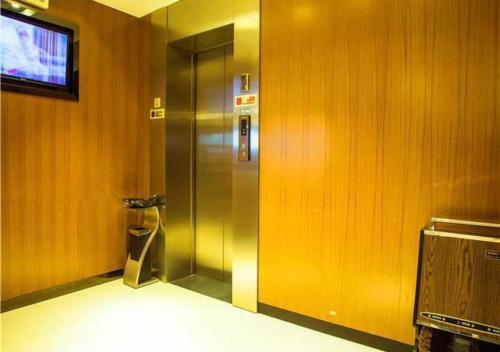 a elevator in a room with wooden walls at JTOUR Inn Wuzhou Arcade City Sanzongfu in Wuzhou