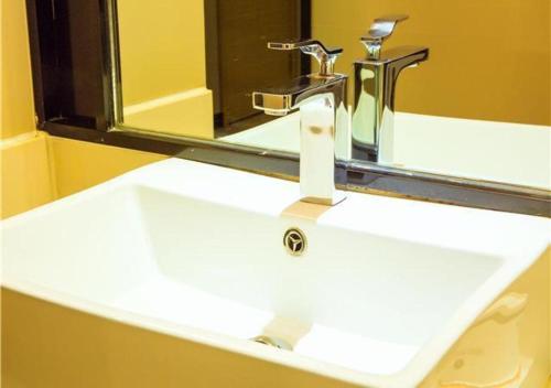 a white sink with a faucet and a mirror at JTOUR Inn Wuzhou Arcade City Sanzongfu in Wuzhou