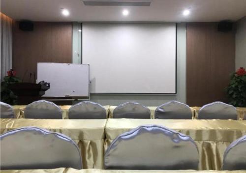 a conference room with a table and chairs and a screen at Borrman Hotel Liuzhou Guizhong Avenue Liugao in Liuzhou