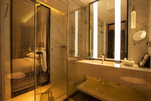 Borrman Hotel Huangshi Daye High-speed Railway North Station Qihao Garden في Daye: حمام مع دش زجاجي ومغسلة