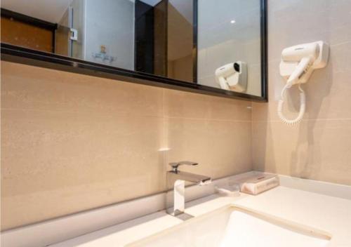 een badkamer met een wastafel en een spiegel bij JTOUR Inn Yulin High-speed Railway Station RT-Mart in Yulin