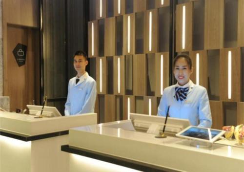 a man and a woman standing in front of a desk at Echarm Hotel Nanning Chaoyang Square River View in Nanning