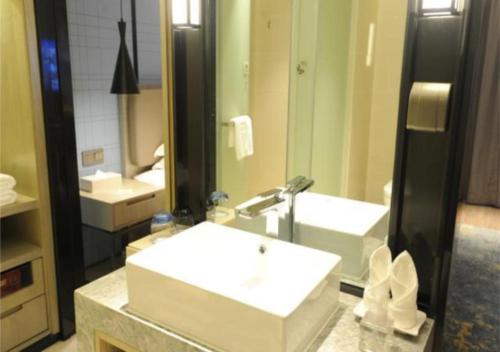 a bathroom with a white sink and a mirror at Echarm Hotel Nanning Chaoyang Square River View in Nanning