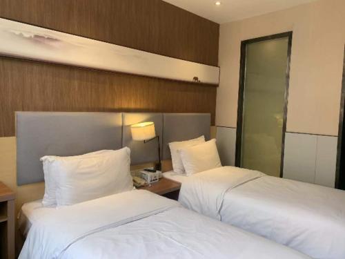 duas camas num quarto de hotel com lençóis brancos em JTOUR Inn Huangshi North Station Cihu Scenic Area em Huangshi