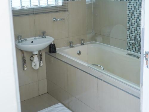 Elam Guest House في امتاتا: حمام مع حوض استحمام ومغسلة
