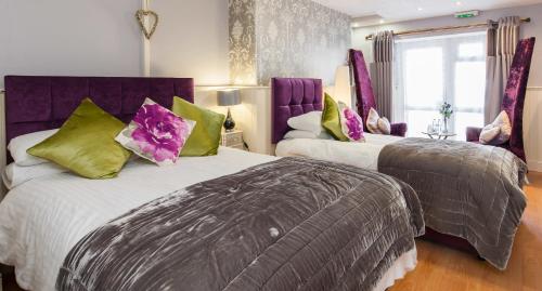 2 bedden in een kamer met paarse en groene kussens bij Rooms by Maes y mor Town Centre in Aberystwyth