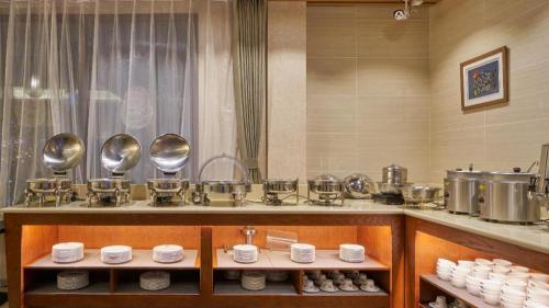 a kitchen with a counter with bowls and dishes at Floral Hotel Birch's Story Harbin in Harbin