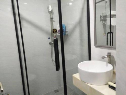 een badkamer met een douche en een witte wastafel bij Ying Feng Yuan Hotel in Guangzhou