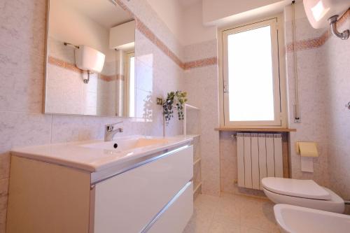un bagno con lavandino, WC e finestra di Orchidea Luxury - Pineto Vacanza a Pineto