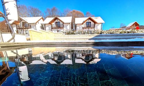 una casa con un reflejo en una piscina de agua en Pallos Apartments, en Sovata