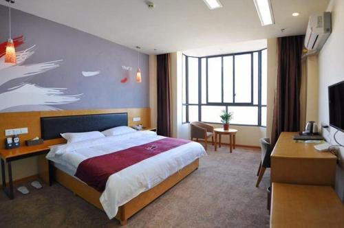 HanyuanにあるThank Inn Hotel Sichuan Ya'An Hanyuan County Huanhu Roadの大きなベッドとデスクが備わるホテルルームです。