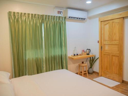 a bedroom with a bed and a green curtain at Turtle Maldives in Omadhoo