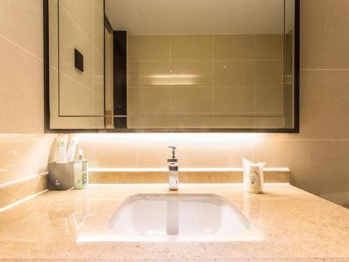 W łazience znajduje się umywalka z lustrem i umywalka. w obiekcie City Comfort Inn Nanning Yudong Jinxiang Metro Station w mieście Nanning