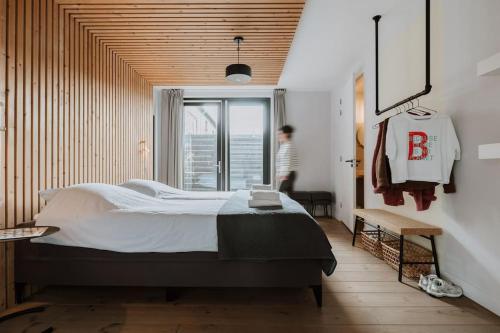 Un dormitorio con una cama grande y una persona mirando por la ventana en HEI15 en Sint Geertruid