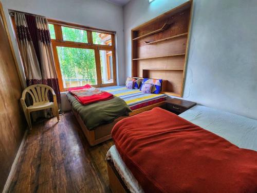 - une chambre avec 2 lits et une fenêtre dans l'établissement Safarnama Homestay Leh - Best Rooms in Leh with Parking, à Leh