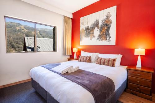 a bedroom with a large bed with a red wall at Lantern 1 Bedroom Apartment in Thredbo