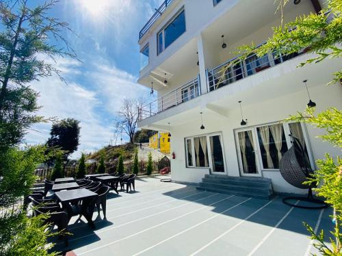 a patio with tables and chairs in front of a building at The Aesthetic Hotel & Restaurant in Bhīm Tāl