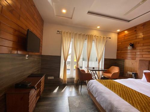 a bedroom with a bed and a desk and a television at The Aesthetic Hotel & Restaurant in Bhīm Tāl