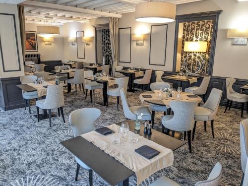 a restaurant with tables and chairs in a room at Hotel Le Lion D'Or et Restaurant La Table Du Lion in Bayeux