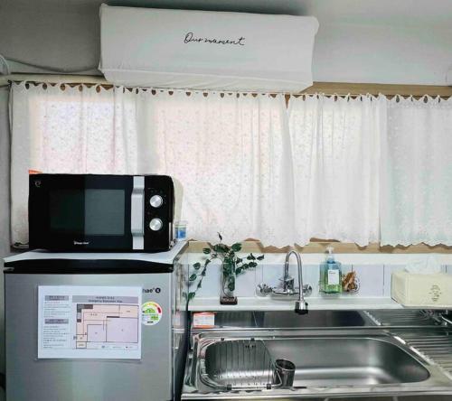 a kitchen with a microwave on top of a refrigerator at Late check-out, Haenggung, Suwon trip, family trip, couple, close to Seoul in Suwon