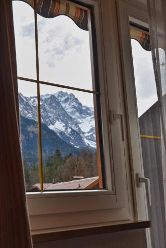 a window with a view of a snow covered mountain at Zum Franziskaner in Grainau