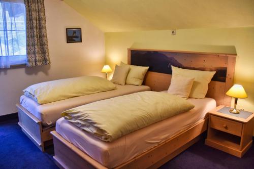 two beds in a hotel room with two lamps at Zum Franziskaner in Grainau