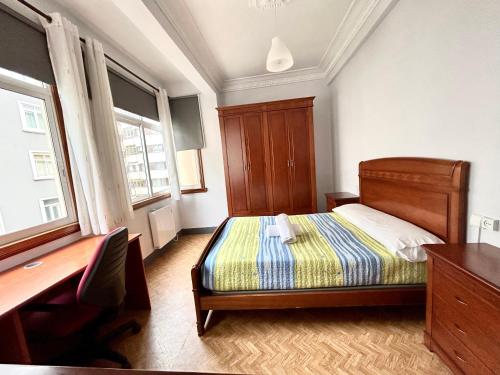 Schlafzimmer mit einem Bett, einem Schreibtisch und Fenstern in der Unterkunft Vibes Coruña-Tovar 42 in A Coruña