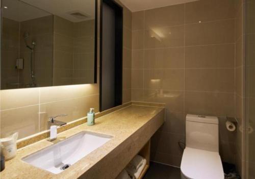 a bathroom with a sink and a toilet and a mirror at City Comfort Inn Liuzhou Liunan Wanda RT-Mart in Liuzhou
