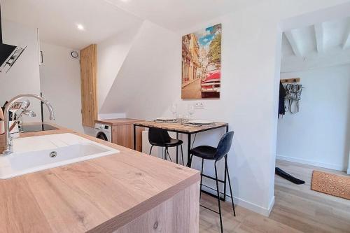 une cuisine avec un évier et une table avec des chaises dans l'établissement La drapière - Maison centre ville, à Louviers