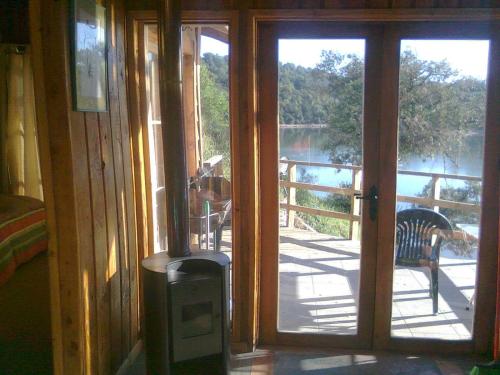 an open door to a balcony with a view of a lake at Cabañas Quillay Viejo in Lago Rapel